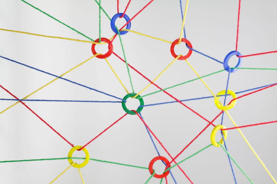 Multicolored strings tied together with different colored rings in red, blue, green or yellow colors making a web.